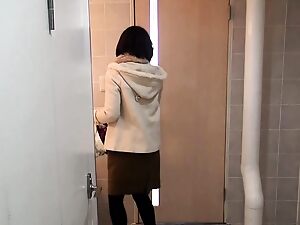 Une femme japonaise urine dans un seau, taquinant.